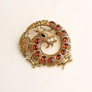 Nahaufnahme der goldenen Vintage Drachen-Brosche mit funkelnden bernsteinfarbenen Strasssteinen.