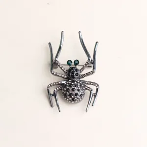 Gros plan d'une broche araignée noire élégante ornée de strass scintillants et d'yeux verts.
