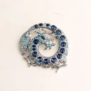 Nahaufnahme einer runden Vintage Drachen Strass Brosche mit blauen Kristallen für Anzüge.