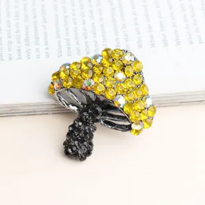 Detailfoto van een stijlvolle paddenstoel broche met gele strass steenen en donkere kristallen.