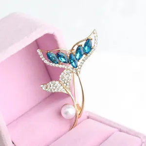 Exquisite fish tail brooch detail featuring sparkling blue crystals and elegant white pearl.