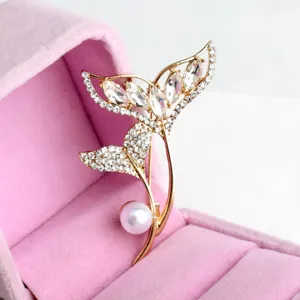 Gold-tone fish tail pearl brooch detailed shot, elegant rhinestone crystal pin accessory.