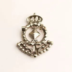 Close up view of the back structure and pin mechanism of a vintage gold tone crown brooch.