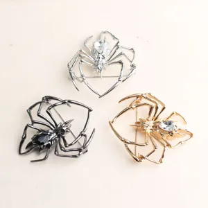 Nahaufnahme von Metall-Spinnenbrosche in Silber, Schwarz und Gold mit funkelnden Steinen.