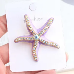 Purple starfish rhinestone brooch or accessory mounted on card, elegant ocean style.