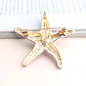 Gold starfish brooch pin with purple enamel details, elegant marine style accessory for women.