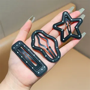 Close-up detail of black leather hair clips with white polka dots in star and cloud shapes.