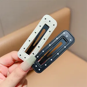 Close-up detail of black and white leather polka dot hair clips, stylish side fringe hairpins.