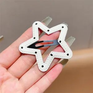Detailed shot of white star-shaped leather hair clip with black dots and metal snap clip.