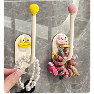 Punch-free wall-mounted storage hook with cute funny face design for hanging hair ties and bands.