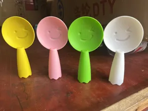 Detail shot of colorful standing rice spoons with cute smiling face designs for kitchen use.