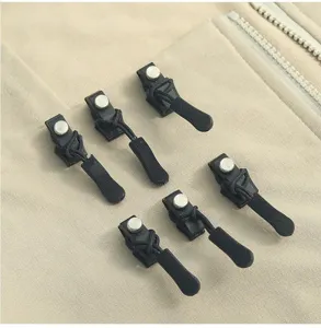 Detailopname van afneembare zwarte ritsreparatieclips en metalen schroeven voor kleding.