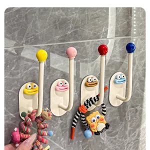 Detail view of colorful wall-mounted storage hooks featuring cute cartoon faces for accessories.