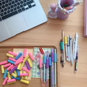 Detailed view of colorful sponge pen grips and stationery accessories on wooden desk