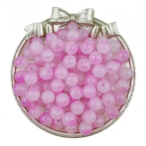 Gros plan de perles rondes acryliques dégradé rose dans un plateau décoratif nœud pour bijoux DIY.