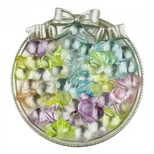 Close-up of colorful translucent acrylic four-leaf clover beads displayed on a silver tray.