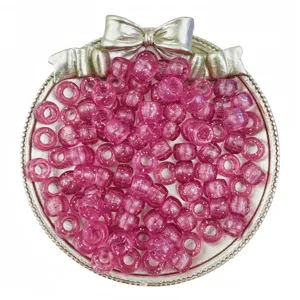 Close-up of sparkling pink pony barrel beads with glitter details inside a silver decorative tray.