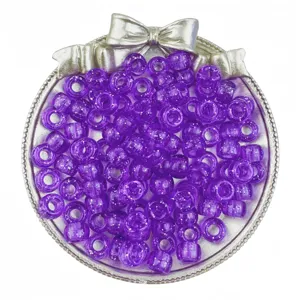 Close-up view of purple glitter pony beads in a silver bow tray for DIY hair braiding.