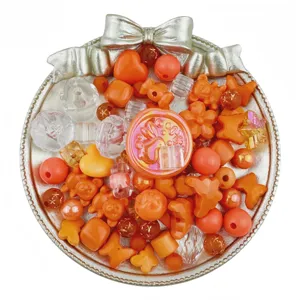 Detailed close-up view of mixed orange and clear acrylic DIY beads, charms and jewelry accessories.