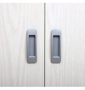 Close-up detail of grey flush pull handle installed on white wood-grain cabinet door surface.