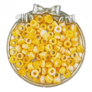 Detailed shot of 6x9mm yellow white swirled pony beads, ideal for hair braiding and DIY crafts.