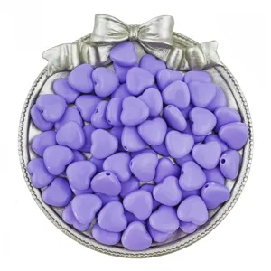 Detail view of purple acrylic heart loose beads inside a silver bow tray for DIY jewelry crafting.