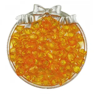 Gros plan détaillé de perles acryliques muguet orange translucide disposées sur un plateau.