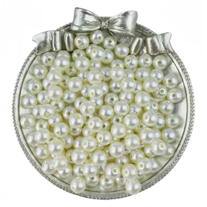 Detail shot of white ABS faux pearls with center holes in silver bow tray for DIY jewelry making.