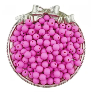 Close-up detail of bright pink matte round beads displayed in a decorative silver bow tray.