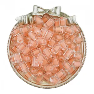 Gros plan de perles cylindriques en acrylique rose dans un plateau décoratif raffiné.