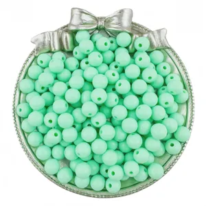 Detail shot of mint green round beads in a silver bow tray, perfect for DIY jewelry making.