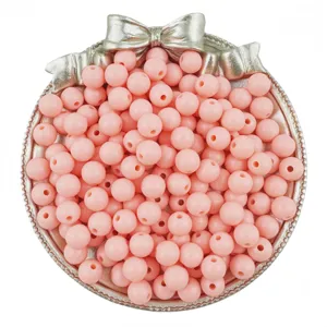 Close-up detail shot of pink acrylic round beads in a silver bow tray for DIY jewelry crafts.