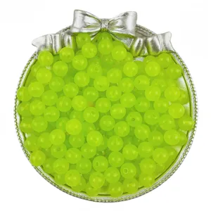 Close-up view of vibrant lime green acrylic jelly beads in a silver bow tray for DIY jewelry.