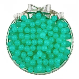 Close-up detail of translucent green acrylic jelly round beads inside a silver bow storage dish.