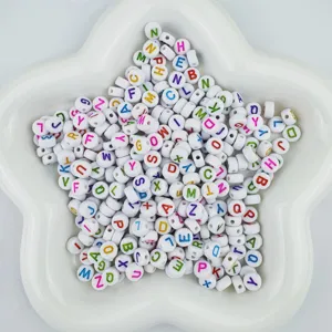 Closeup of 4x7mm white acrylic letter beads with colorful alphabet prints for DIY jewelry making.