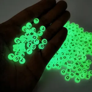 Close-up of luminous acrylic letter beads showing glowing green effect in dark for DIY crafts.