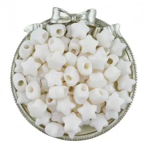 Close-up detail of white acrylic star beads in decorative silver tray, DIY jewelry making.