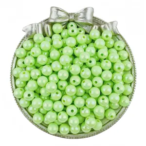 Detail shot of light green acrylic AB round beads in a silver bow tray for DIY jewelry crafts.