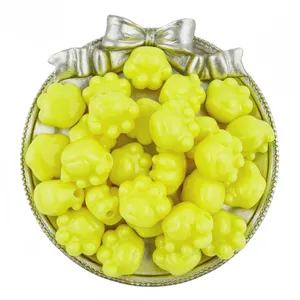 Close-up of bright yellow acrylic cat paw beads with horizontal holes for DIY jewelry.