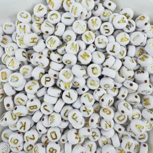 Close-up detail of white acrylic letter beads with gold letters for DIY jewelry and bracelets.