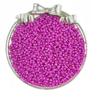 Vibrant magenta glass seed beads in decorative silver tray, perfect for DIY jewelry making.