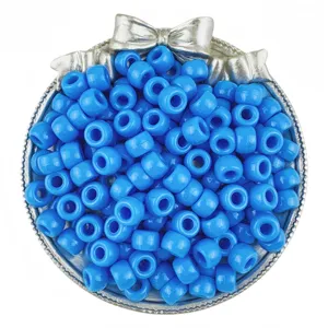Detailed view of bright blue pony beads in a silver bow dish, perfect for DIY hair braiding.