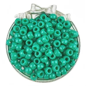 Close-up detail of vibrant teal pony beads in a decorative silver bow bowl for DIY crafts.