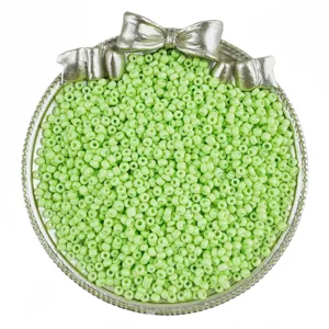 Light green glass seed beads in a silver bow tray, perfect for DIY jewelry making crafts.