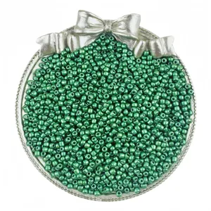 Close-up detail of sparkling green glass seed beads in a silver bow container for DIY craft.
