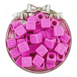 Close-up view of pink acrylic letter cube beads displayed in a charming decorative bow tray.