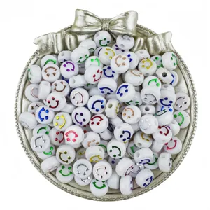 Detail shot of white acrylic smiley face beads in a silver bow tray, DIY jewelry making.