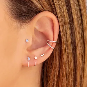 Gros plan detail des boucles d'oreilles celestes argentees avec etoiles, lune et eclair.