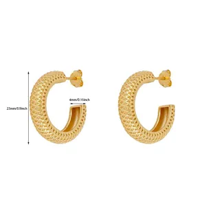 Goldene strukturierte C-förmige Creolen im Detail, stilvoller Netzmuster Schmuck Nahaufnahme.
