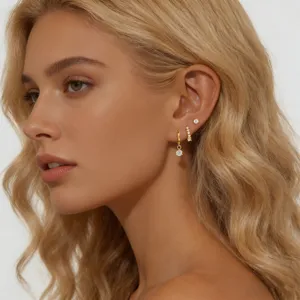 Primer plano detallado de un conjunto de pendientes dorados con circonitas, diseño elegante.